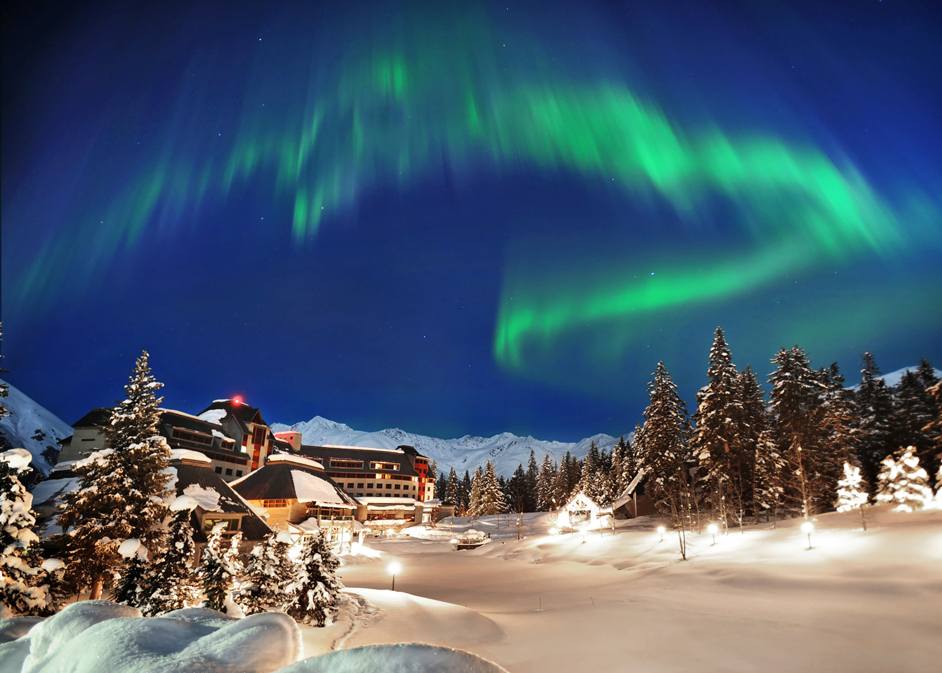 The Hotel Alyeska under green northern lights on a snowy winter night