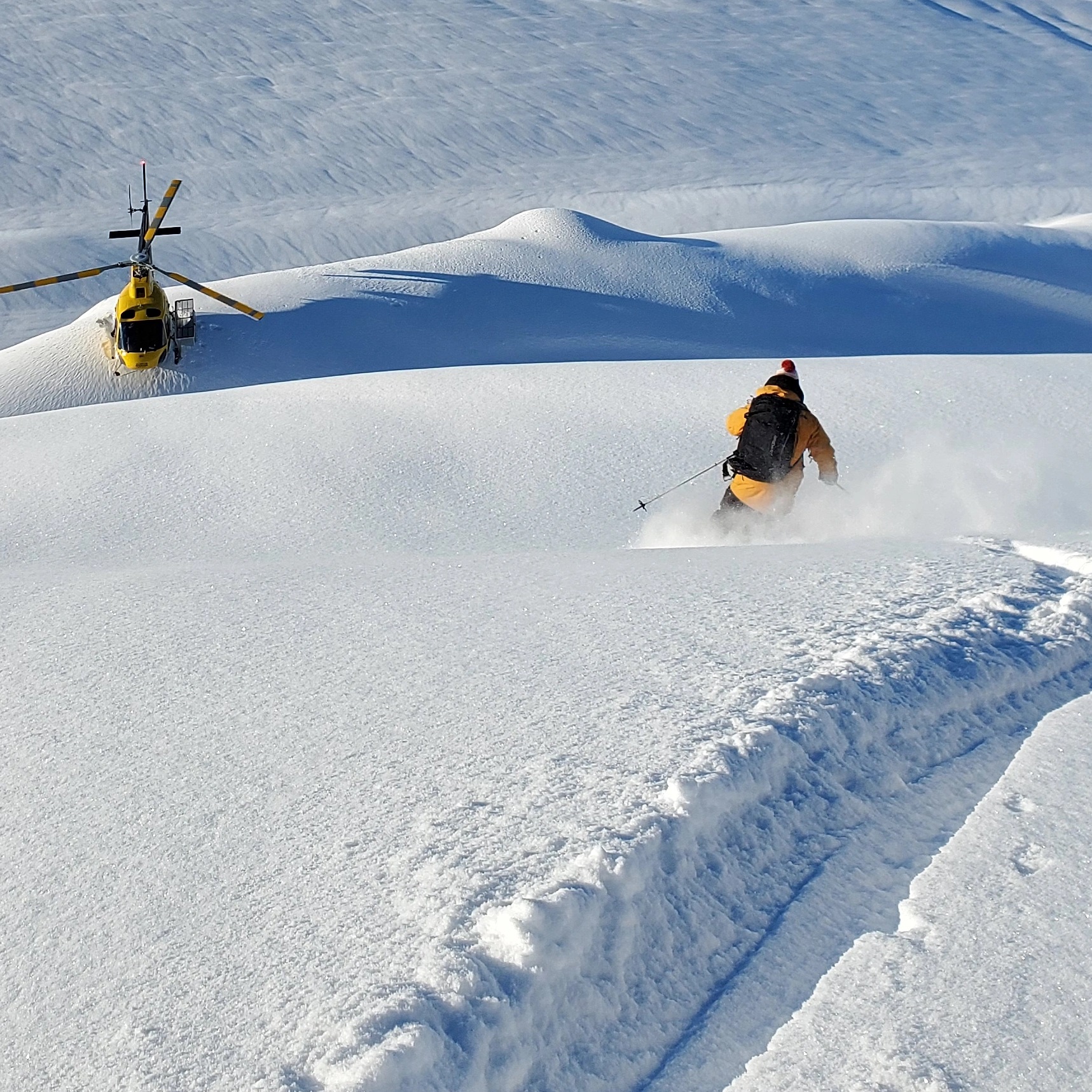 SMG guest carving through deep powder on a steep Alaska mountain slope
