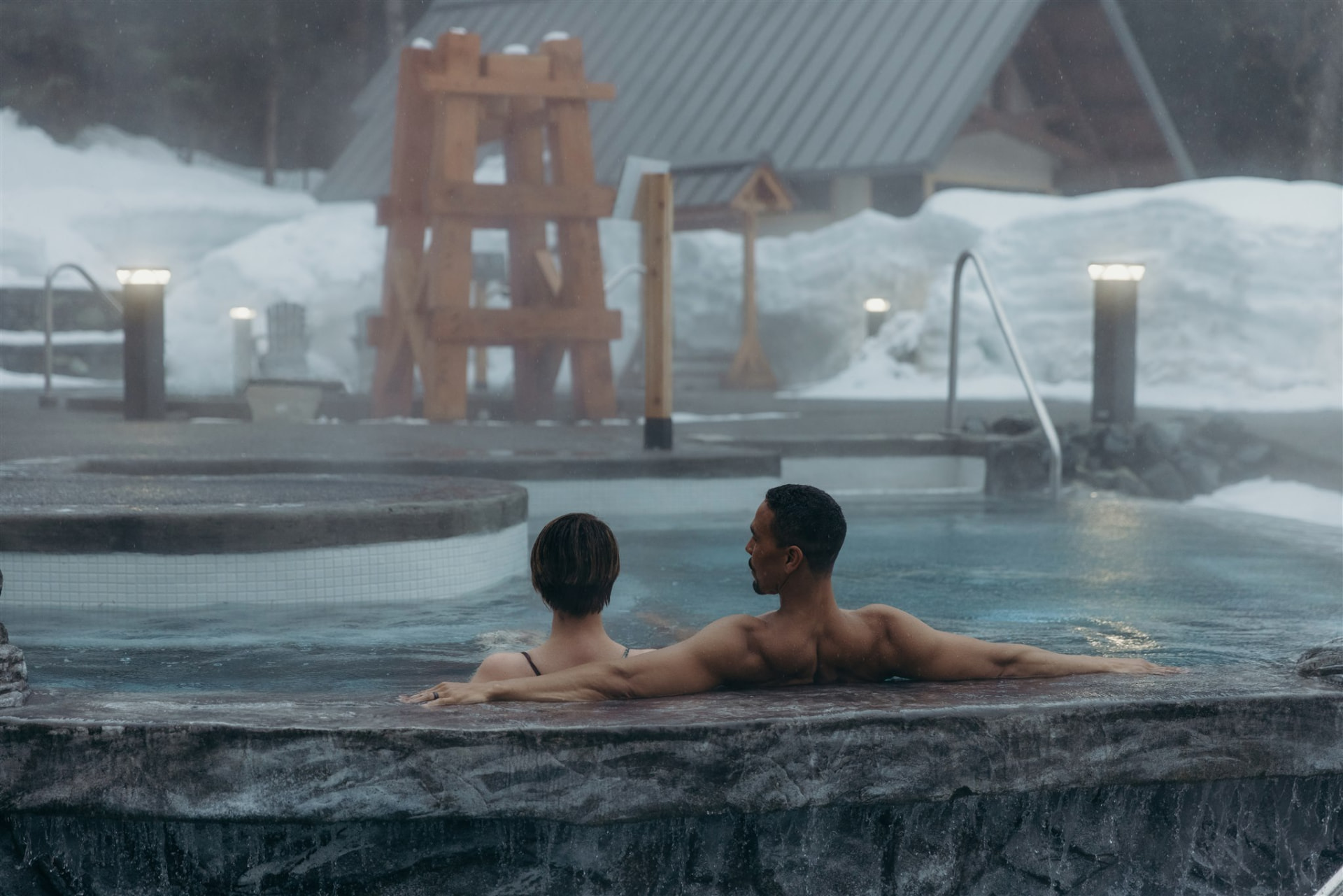 Guests in a steaming outdoor relaxation pool at the Alyeska Nordic Spa