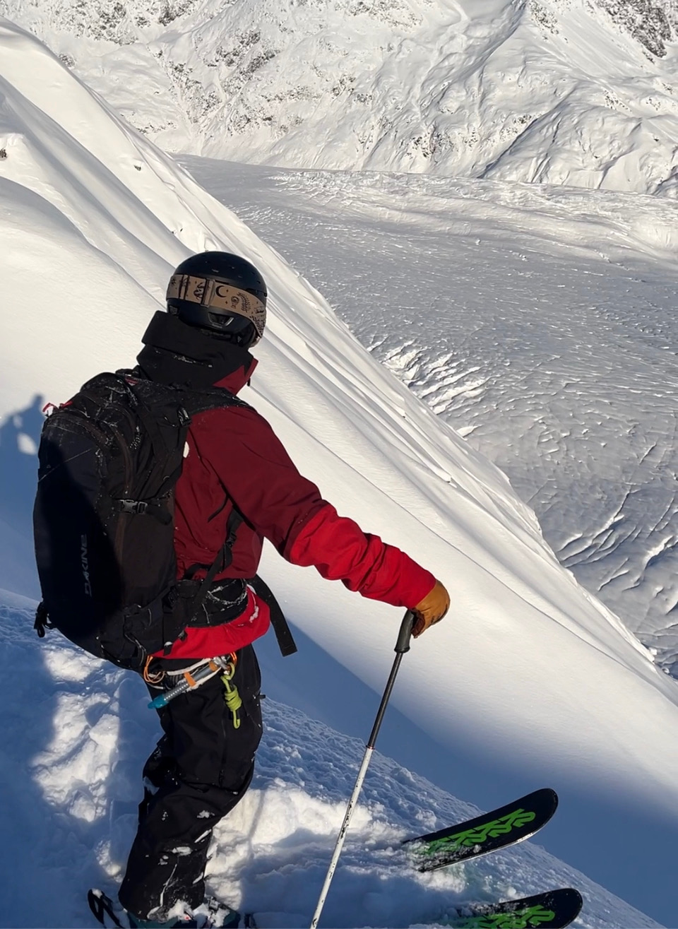 SMG guest in a red jacket on a steep Alaskan ridge above a glacier