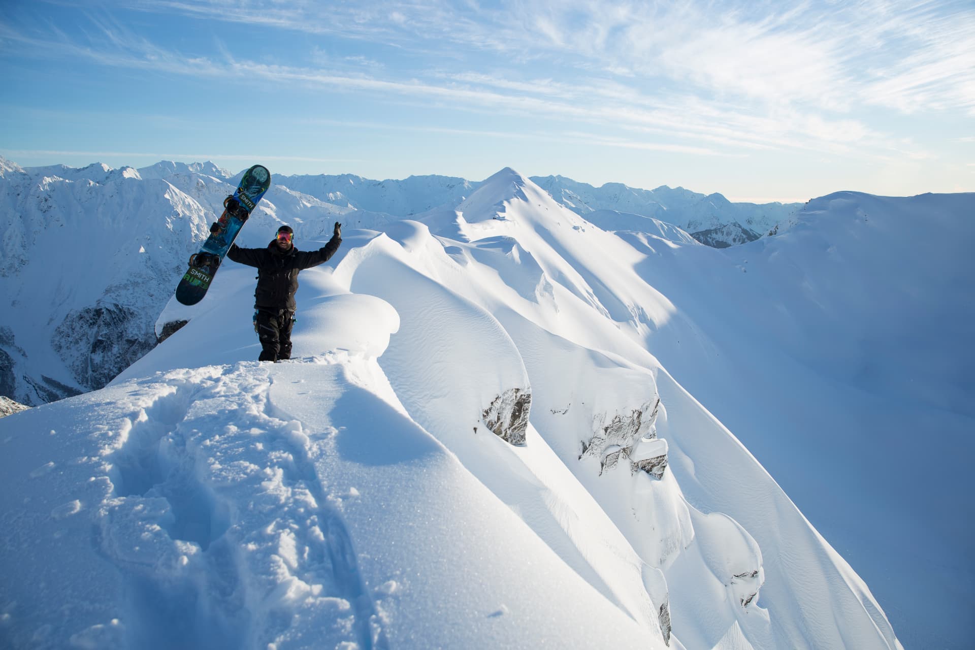 SMG heli skier descending an untracked Alaska face above the ocean