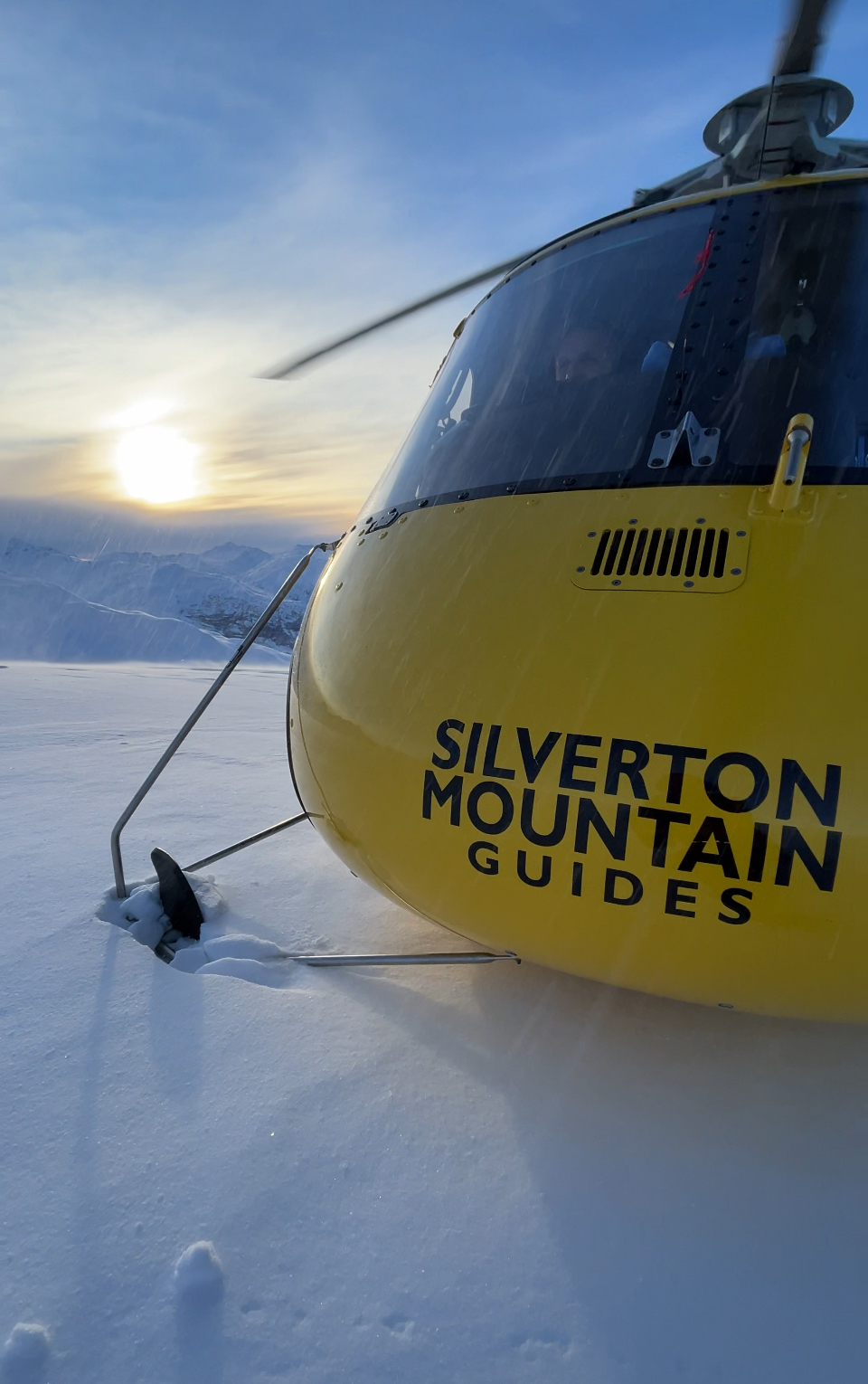 SMG's yellow helicopter parked on an Alaska snowfield at sunrise before the first flight of the day